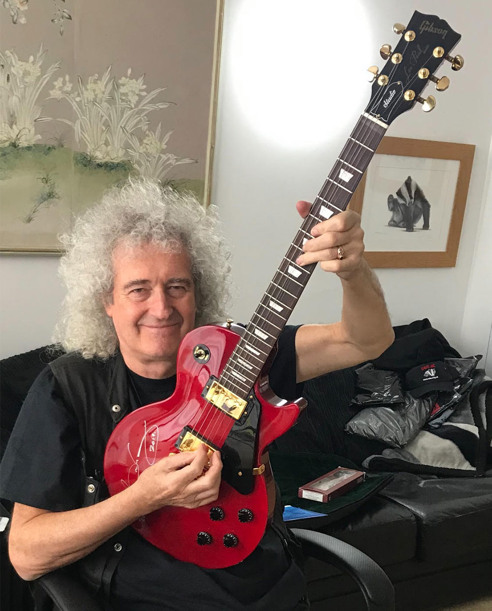 Older man holding red guitar