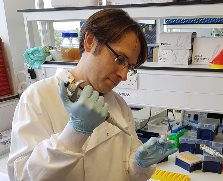 Photo of brown haired man with glasses working in lab