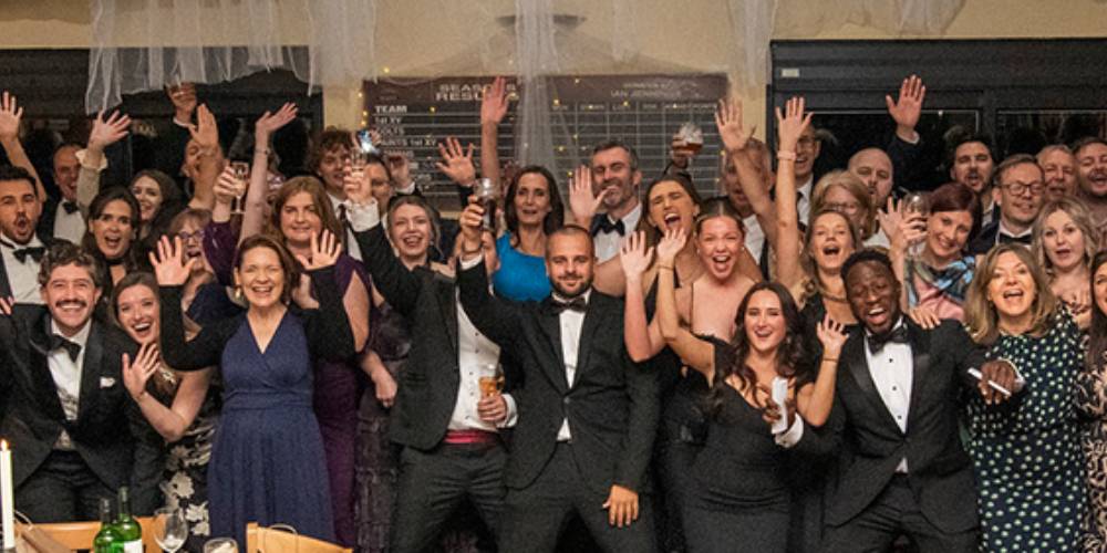 100+ people dressed up at a ball all face camera for group photo