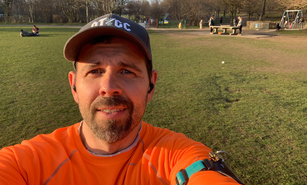 Man with orange sports top in open park