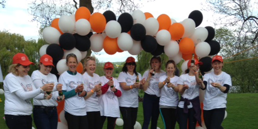 Approx 20 walkers under orange, white and black balloon wreath
