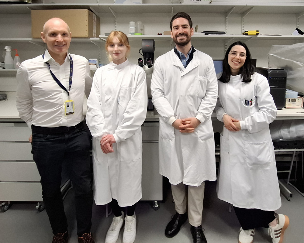 4 researchers smiling in lab coats